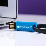 Niebieski pendrive z logo Windows 10 podłączony do laptopa.
